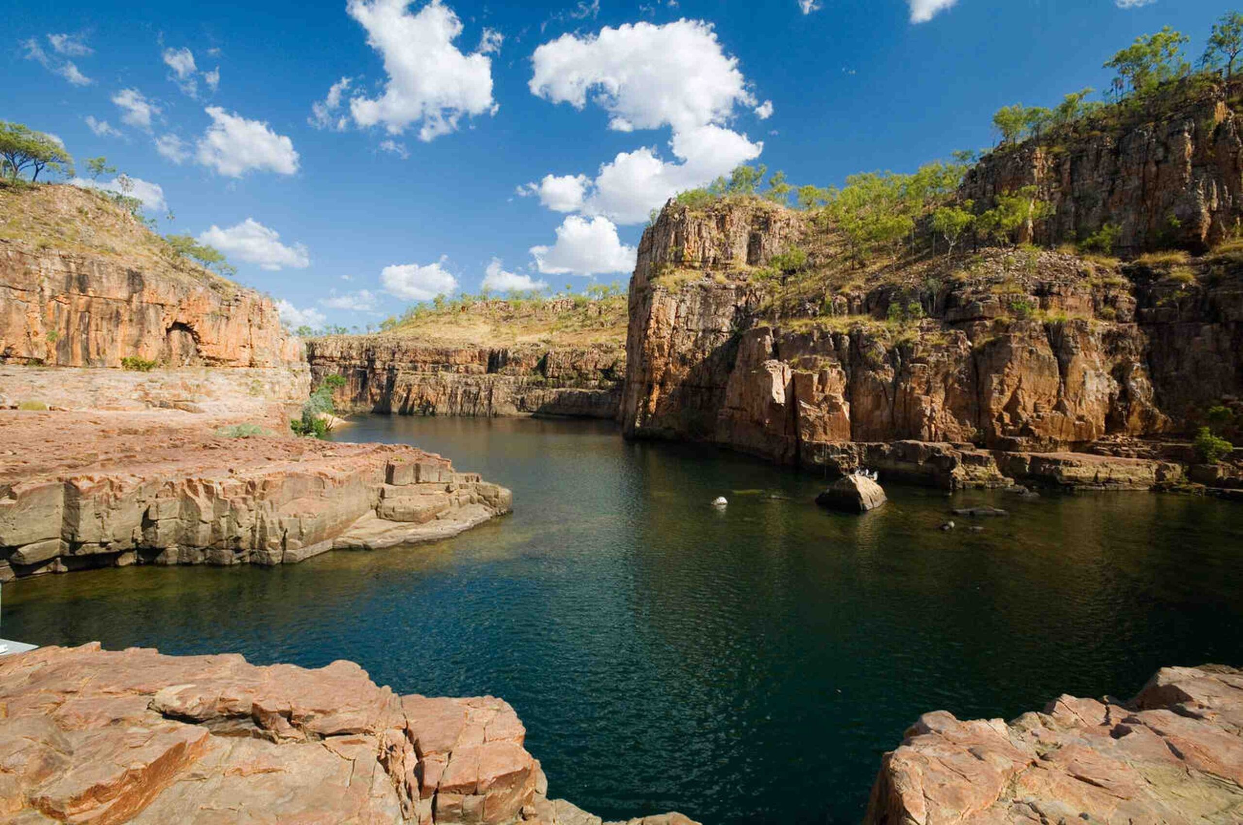 The stunning Katherine Gorge in Nitmiluk National Park, featuring dramatic cliffs, clear blue waters, and lush greenery.