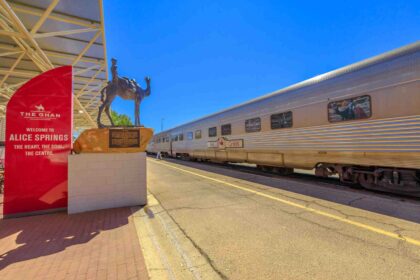 The Ghan train at Alice Springs station with a camel statue, showcasing the iconic Australian outback journey through the Northern Territory