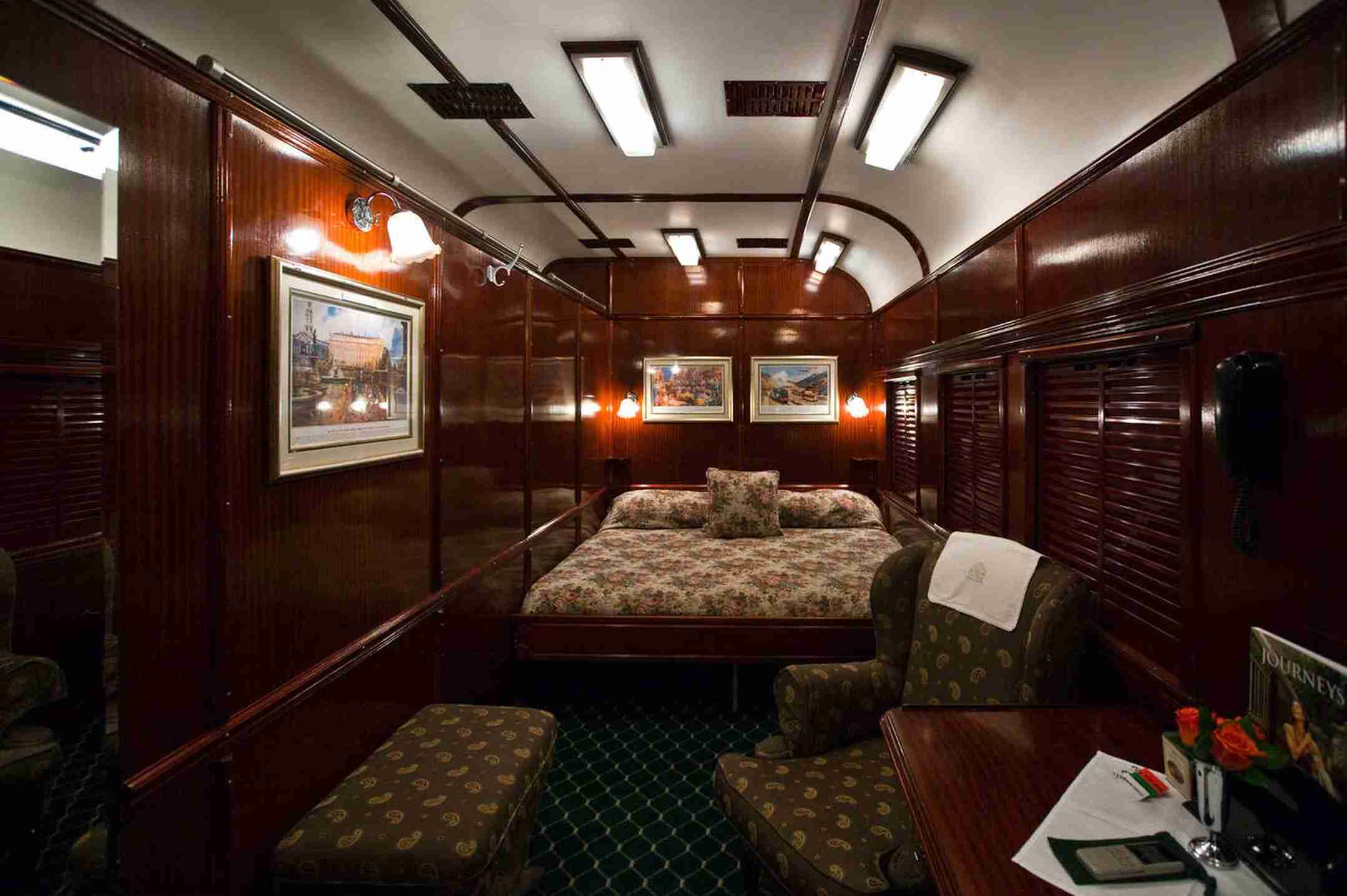 Luxury cabin interior of The Ghan train featuring a cozy bed and elegant wooden design