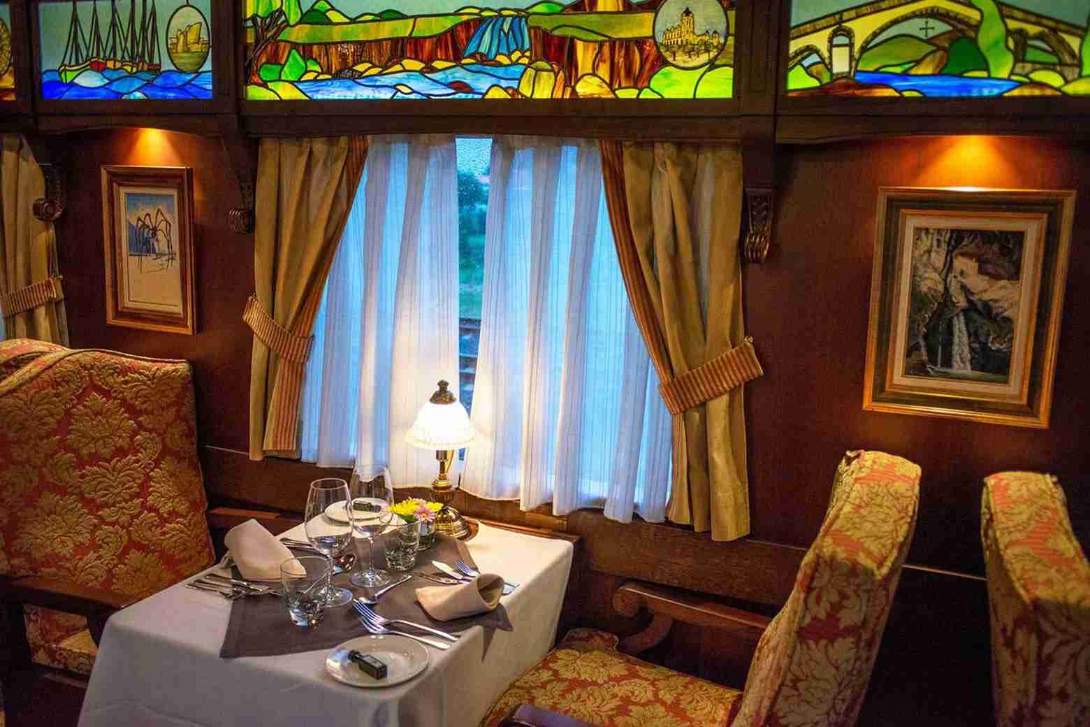 Elegant dining setup aboard The Ghan train with stained glass windows | Elite Rail Journey